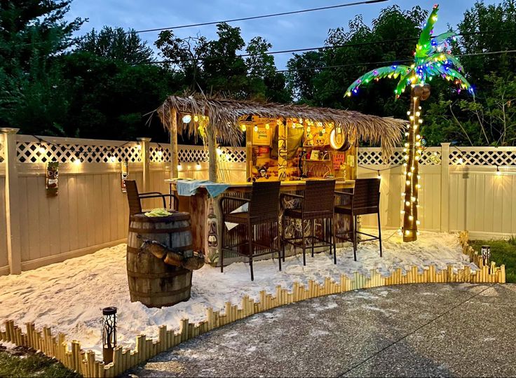 a backyard with a tiki bar and lights on the side of it, surrounded by snow