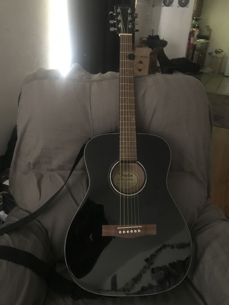 a black guitar sitting on top of a couch