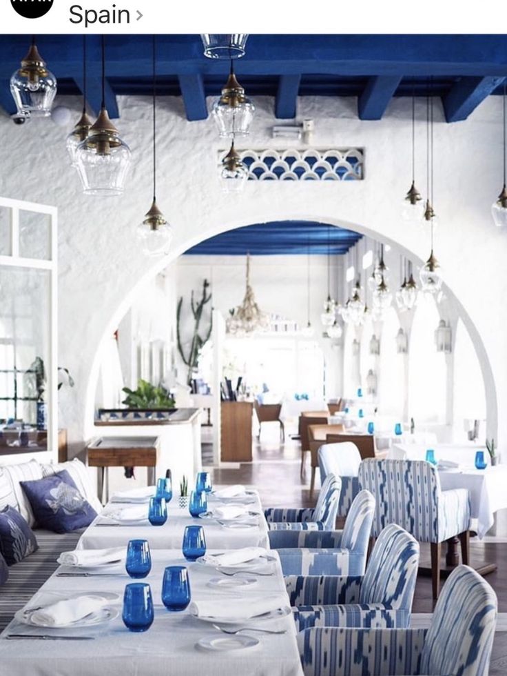 a dining room with blue and white chairs, table cloths and plates on the tables