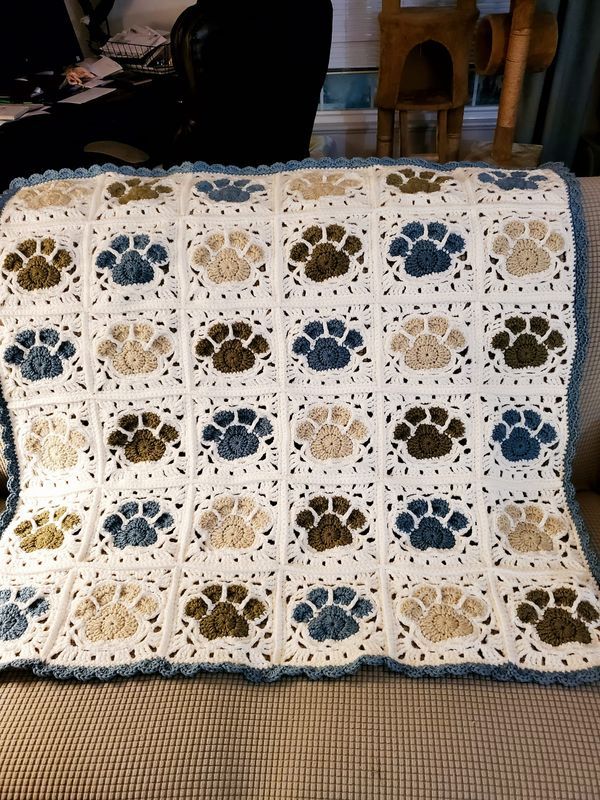 a dog's paw print crochet afghan on a couch