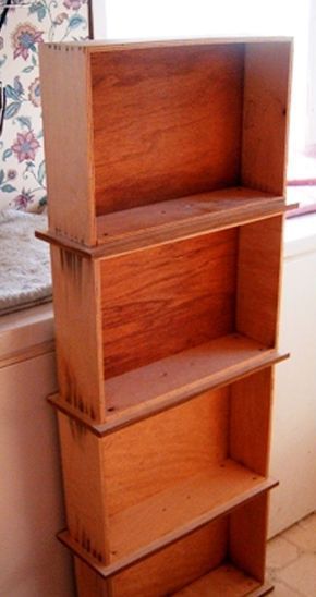 three wooden bookshelves stacked on top of each other in front of a window