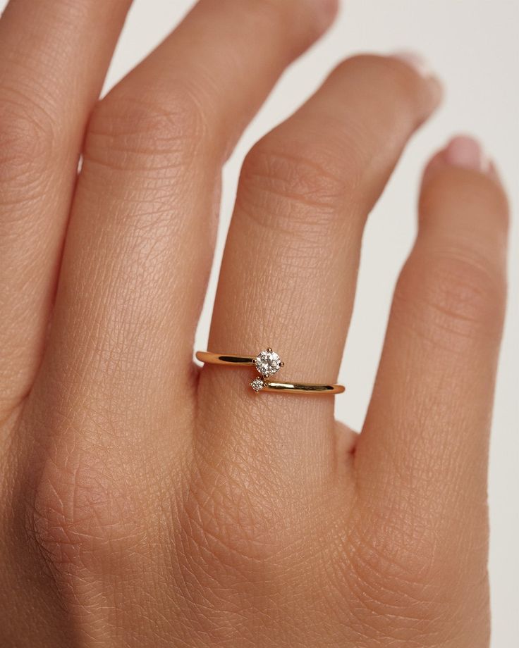 a woman's hand with a diamond ring on top of her finger, against a white background