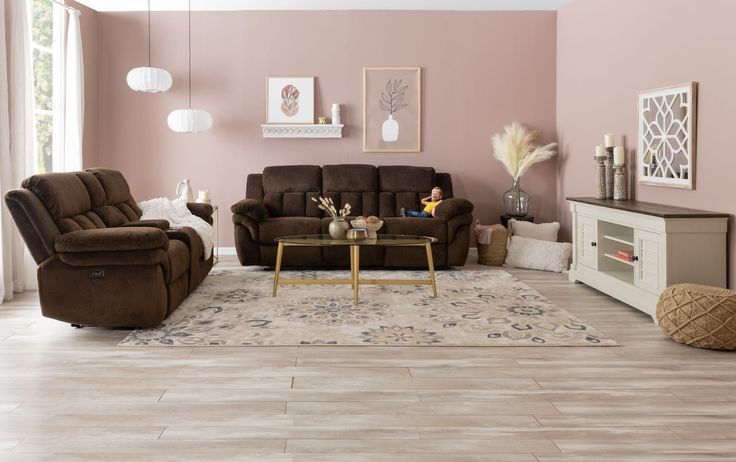 a living room with two couches and a coffee table in front of a pink wall