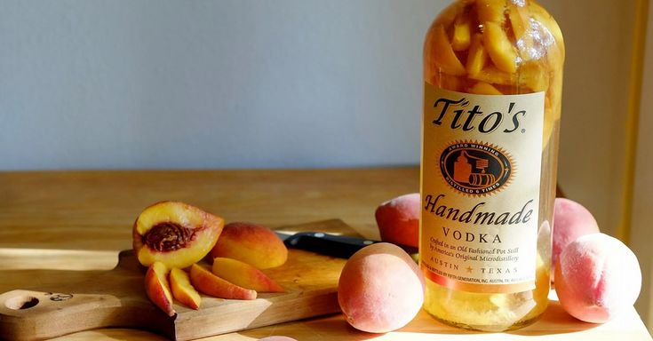 a bottle of wine sitting on top of a table next to sliced peaches and a knife