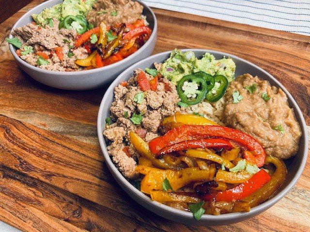 two bowls filled with food sitting on top of a wooden cutting board