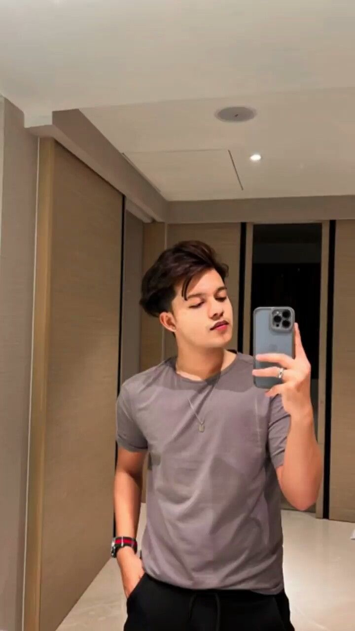 a young man taking a selfie with his cell phone in front of the mirror