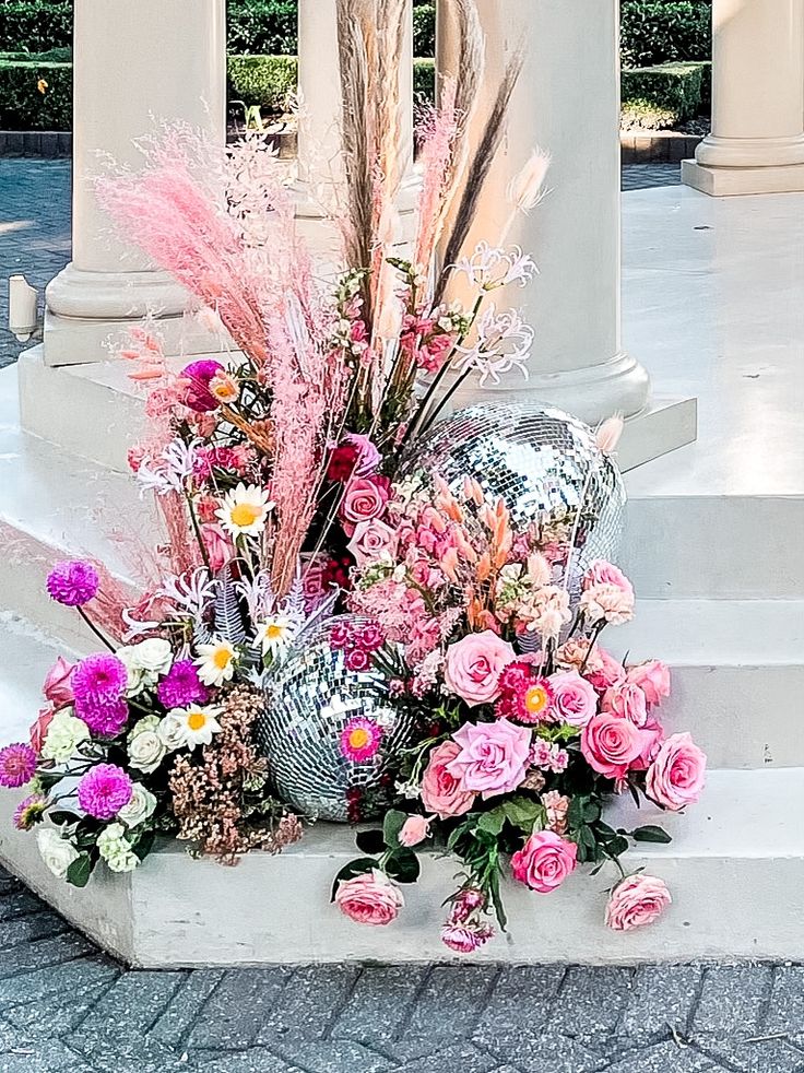 a vase filled with lots of flowers sitting on top of a cement slab next to some stairs