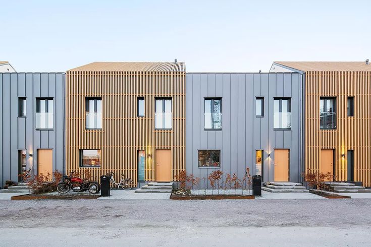 three buildings with wooden slats on the sides and bicycles parked in front of them