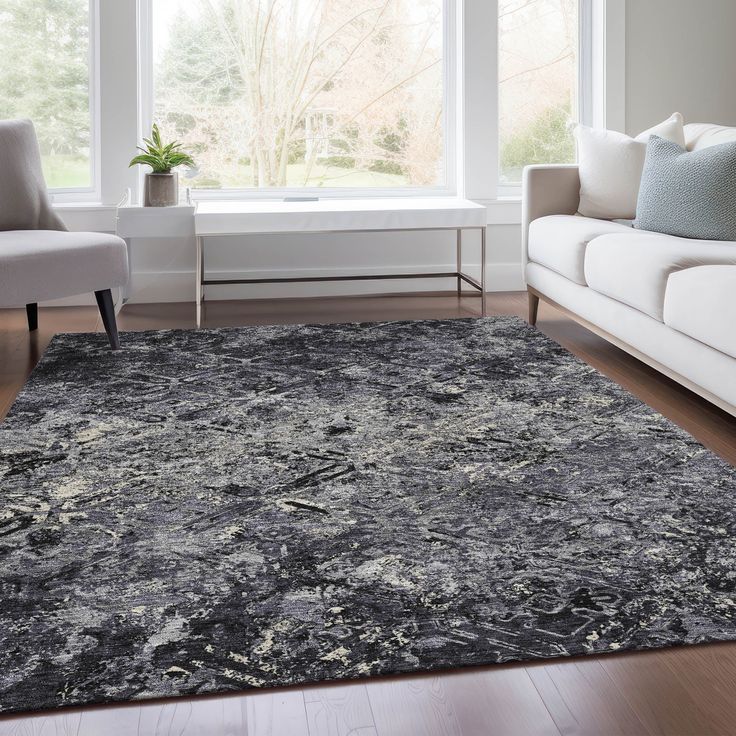 a living room area with couches, chairs and a rug on the hardwood floor