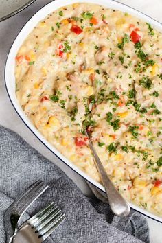 a casserole dish with chicken and vegetables in it on a table next to silverware