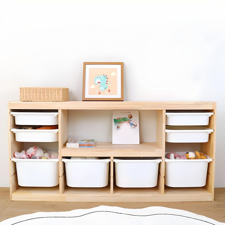 a wooden shelf with white containers on top of it next to a rug and pictures