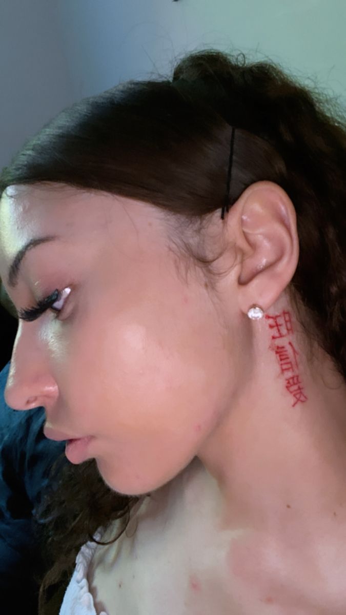 a woman with tattoos on her neck and ear