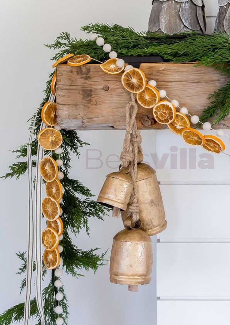 a bunch of oranges that are hanging from a wooden beam with bells attached to it