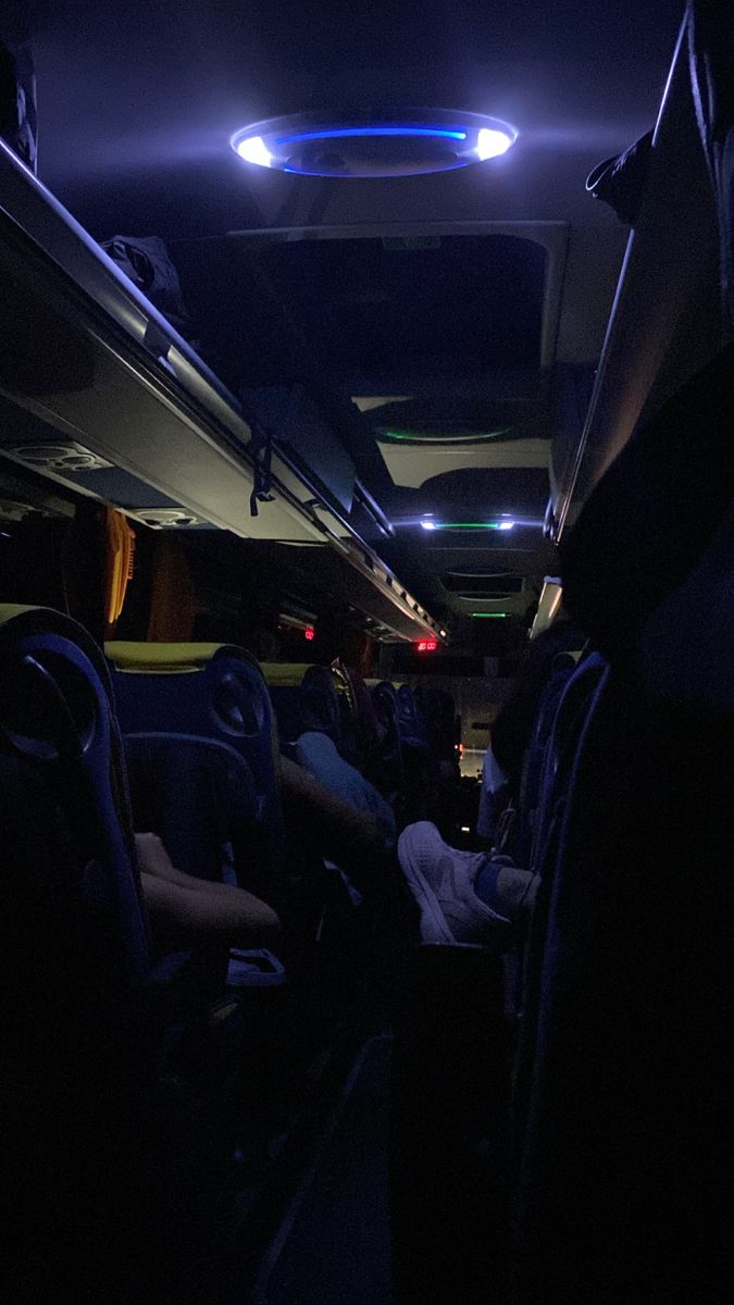 the interior of a bus at night with people sitting in seats and one person standing up