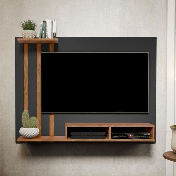 a flat screen tv mounted to the side of a wooden shelf next to a potted plant