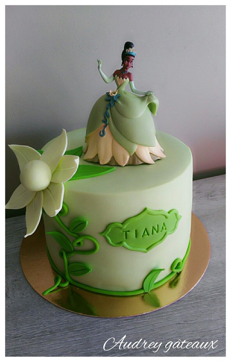 a green and white cake with a lady on top