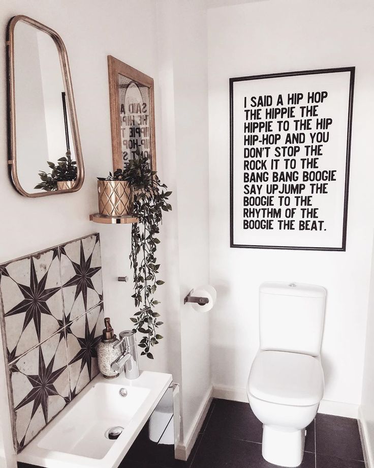 a white toilet sitting next to a bathroom sink under a framed art piece on the wall