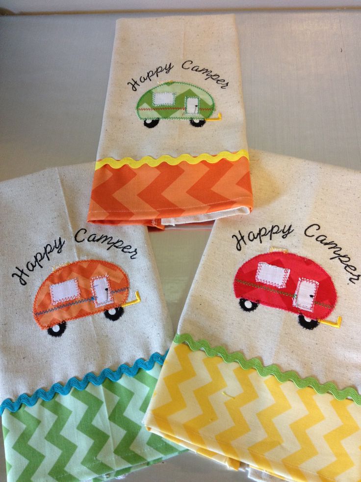 four hand towels with embroidered campers and happy campers on them, sitting on a table