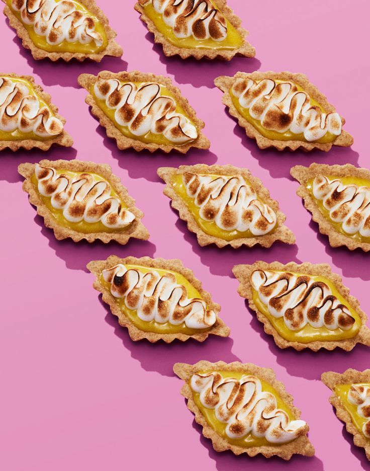 many small pastries are arranged on a pink surface