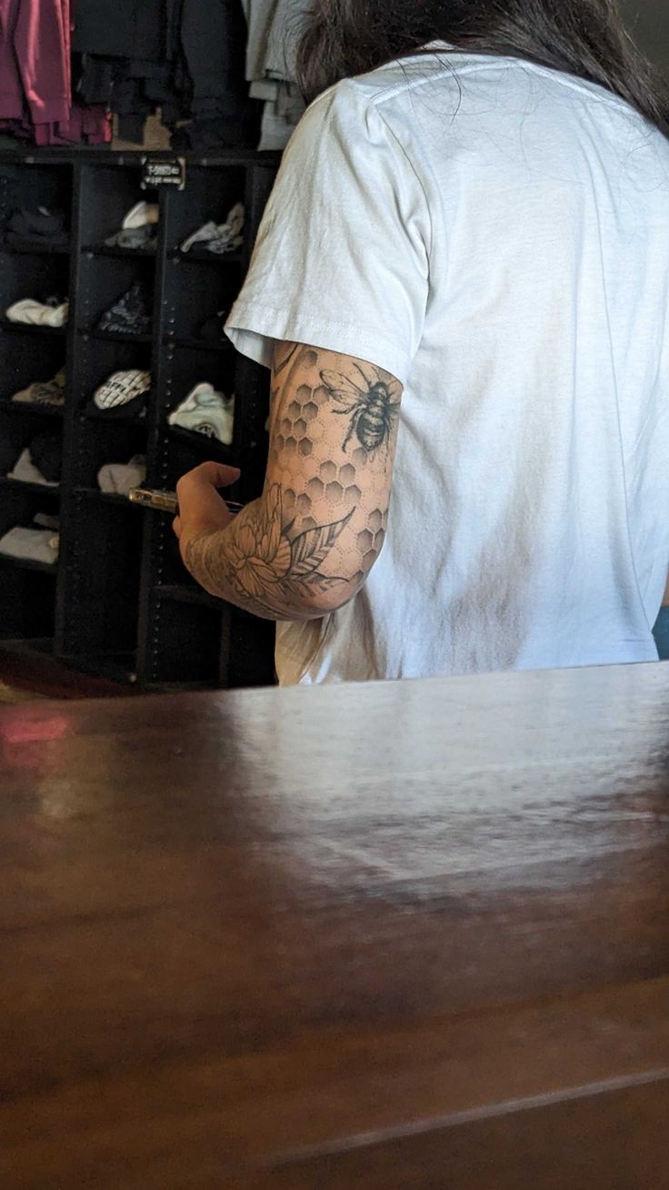 a man with a tattoo on his arm sitting at a table in front of some shoes