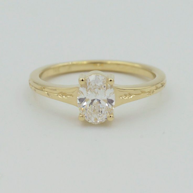 a yellow gold ring with an oval cut diamond in the center, on a white background