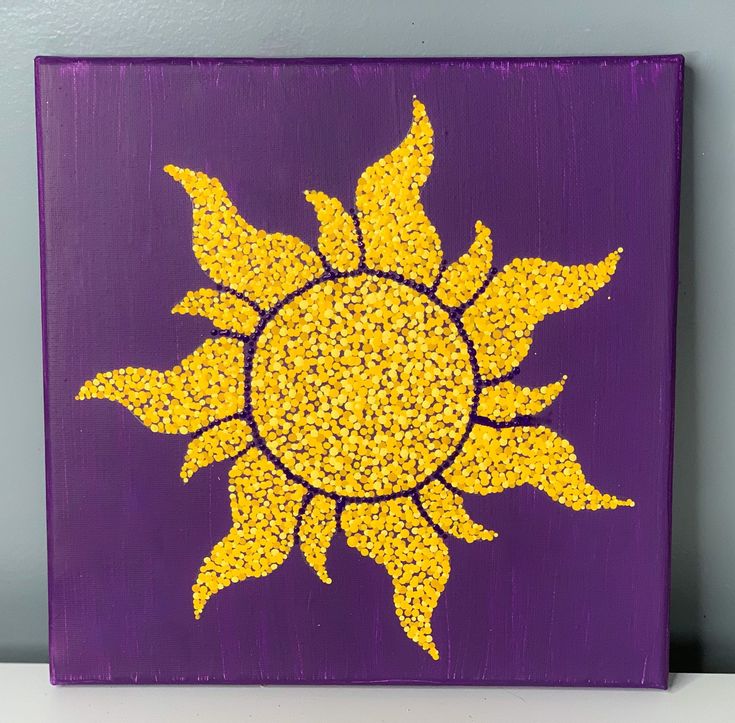 a purple and yellow painted canvas with the sun in it's center on a shelf