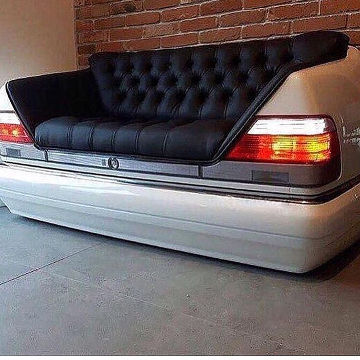 a black and white couch sitting on the back of a car in front of a brick wall