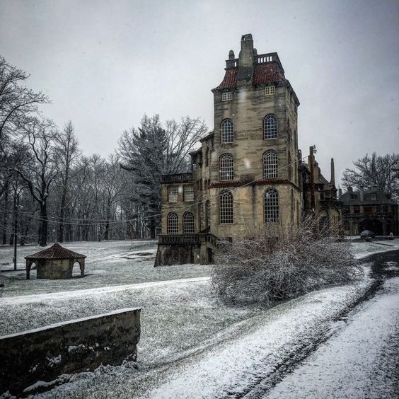 an old house with snow on the ground and trees in the backgroung