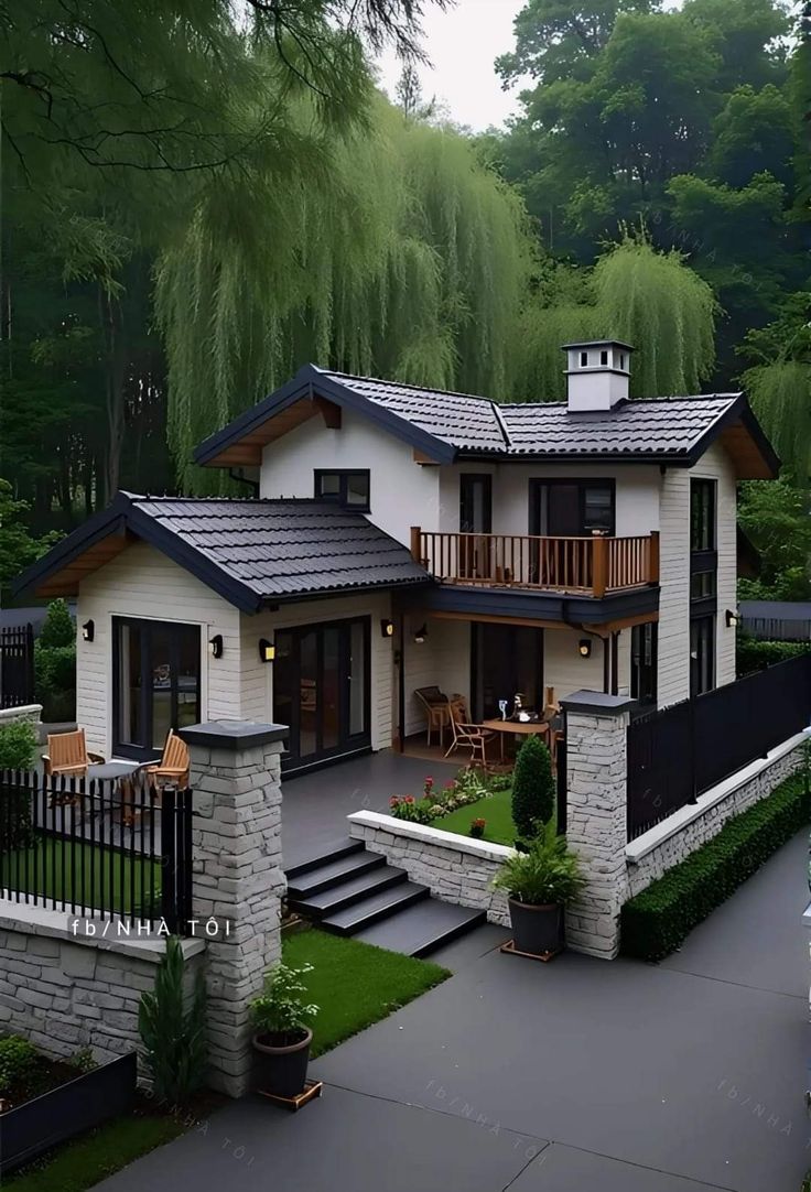 a large white house surrounded by trees and greenery with stairs leading up to the front door