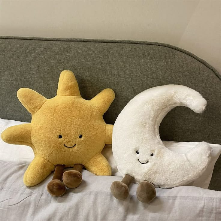 two stuffed animals sitting on top of a bed next to each other in front of a pillow