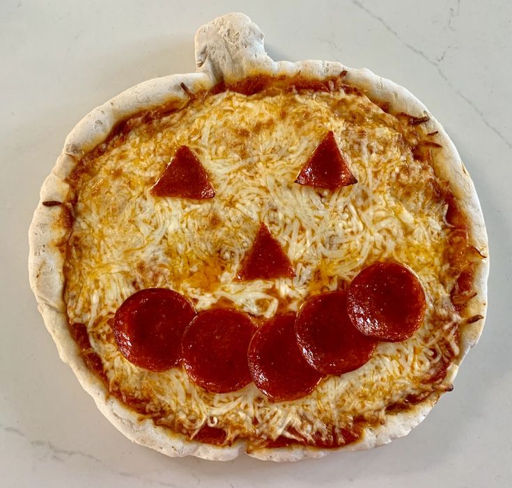 a pizza topped with cheese and pepperoni on top of a white countertop next to a knife