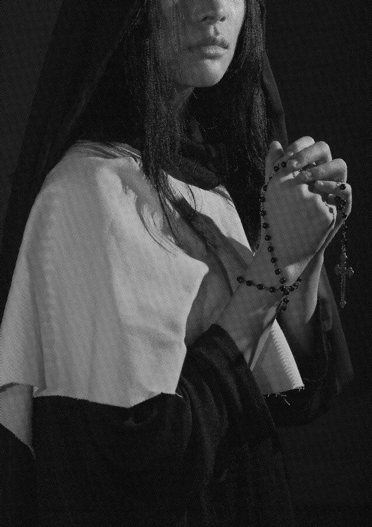 black and white photograph of a woman wearing a nun outfit holding a rosary in her hands