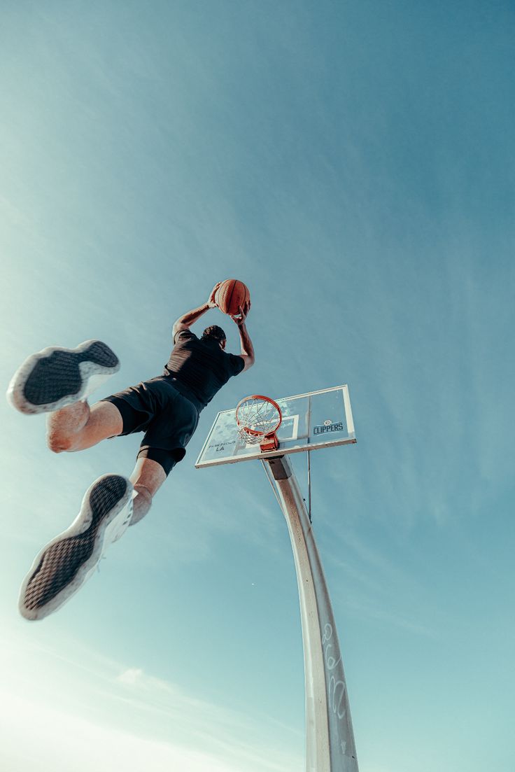 a person jumping up into the air to dunk a basketball in front of a hoop