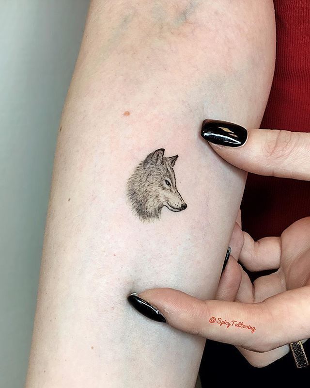 a woman's arm with a small tattoo of a wolf on her left side