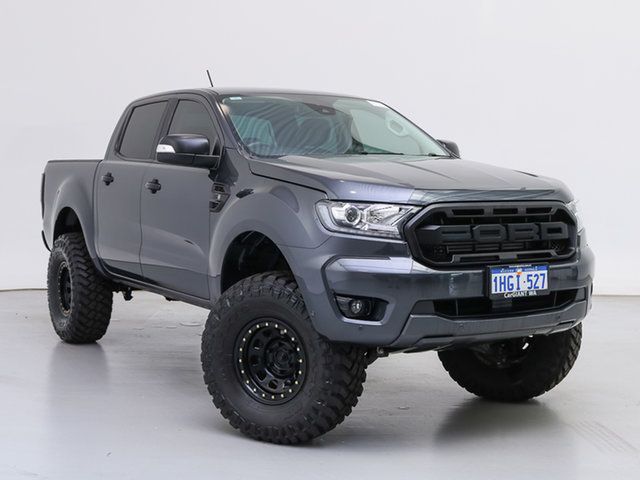 a grey truck is parked in a room with white walls and black tires on it