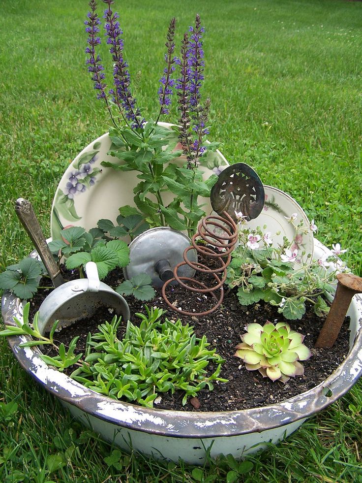 a potted planter filled with plants and gardening implements on top of green grass