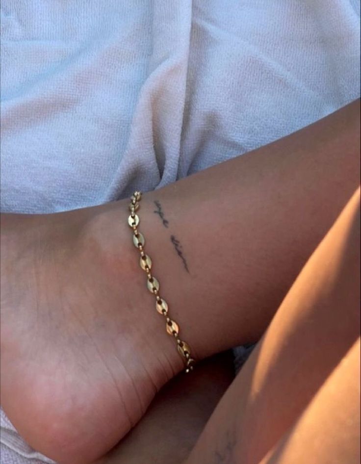 a close up of a person's foot with a gold chain on the ankle