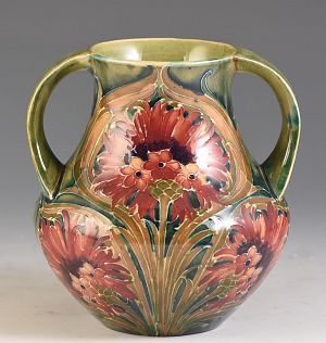 an ornate vase with flowers painted on the outside and inside, sitting on a white surface