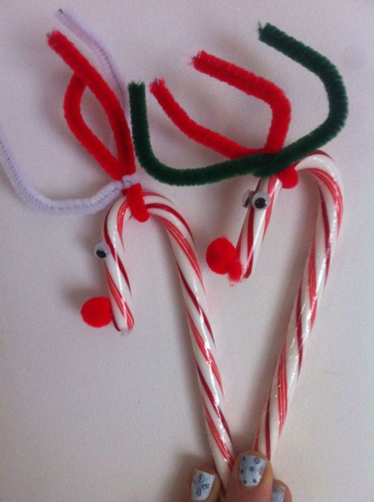 some candy canes are being held up by someone's hand with red and green decorations on them