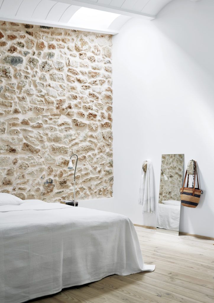 a bedroom with stone walls and white bedding