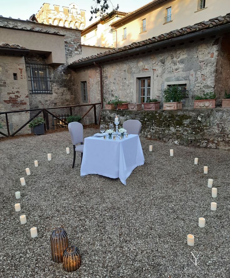 a table set up outside with candles on the ground in front of an old building