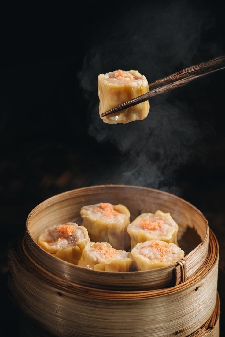 some food is being cooked in a bamboo steamer with chopsticks sticking out of it