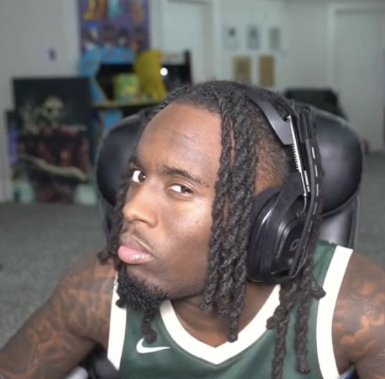 a man with dreadlocks and headphones sitting in front of a computer desk