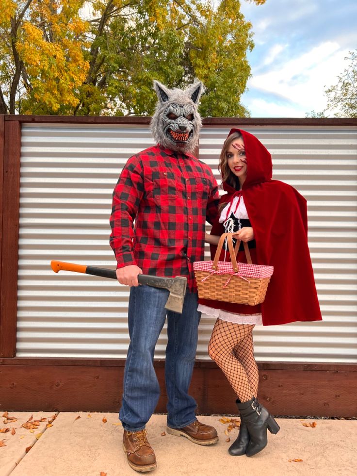 a man and woman dressed up in costumes standing next to each other, one holding a bat