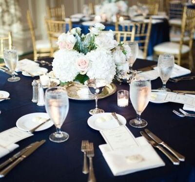 the table is set with silverware and white flowers