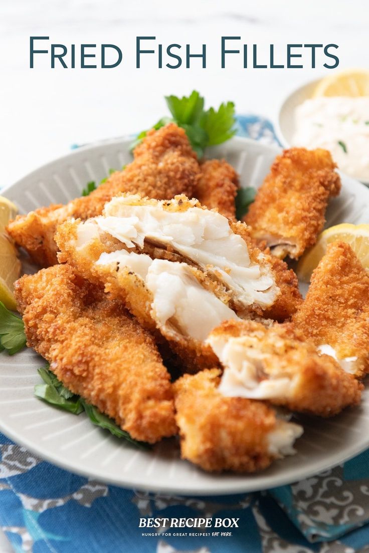 fried fish fillets on a plate with lemon wedges