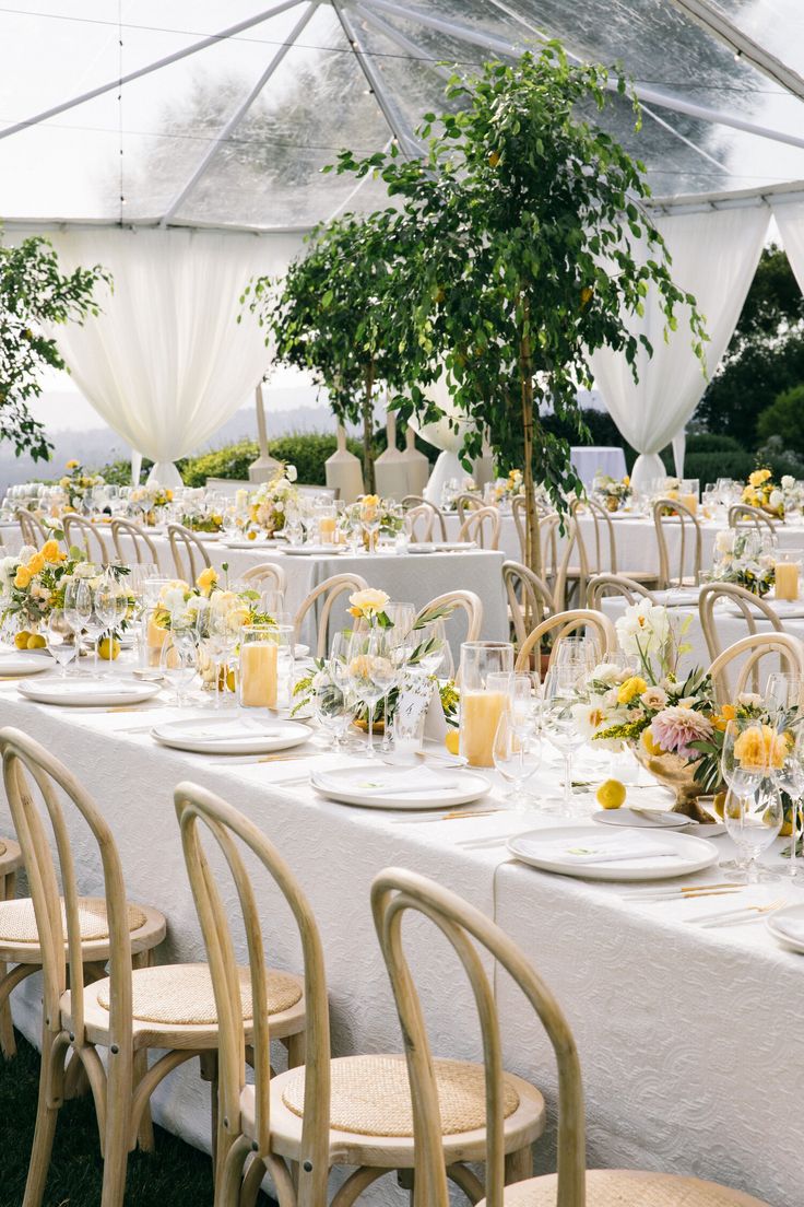 the tables are set with white linens and yellow flowers