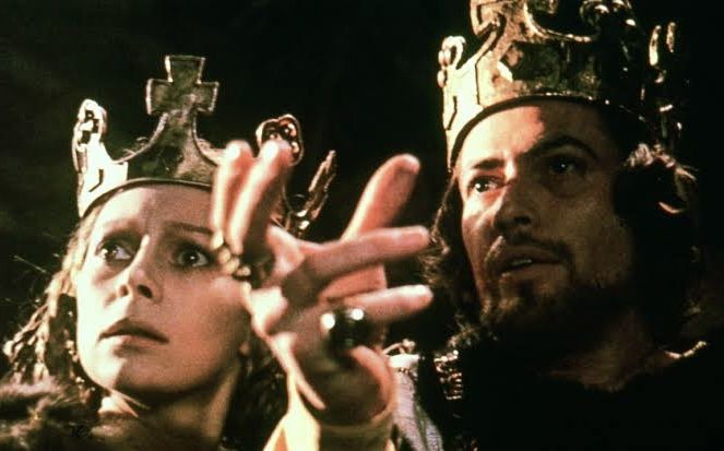 two people dressed as king and queen holding their hands up