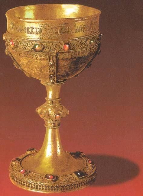 an ornate gold cup with red stones on the bottom and sides is shown in this image