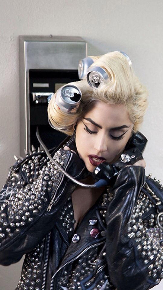 a woman with rollers on her head talking on a cell phone while wearing a leather jacket